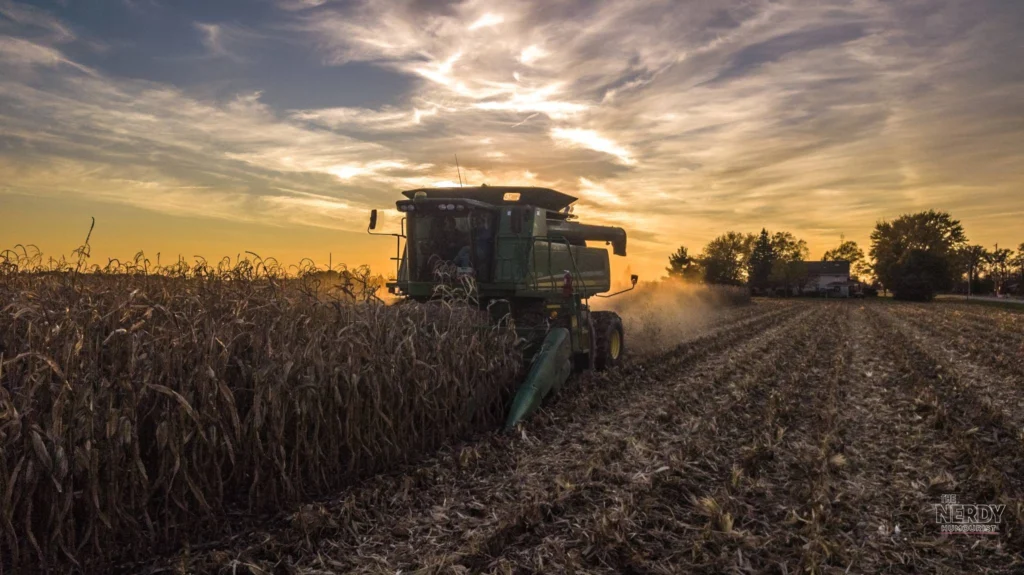 Combine harvester harvesting corn at sunset as Trump announces $8 billion harvest fuel relief program for farmers.