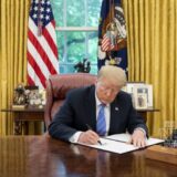 President Donald Trump signing an executive order at the Resolute Desk, illustrating the Trump Russia sanctions waiver.