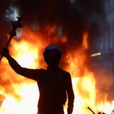 A masked protester raises an arm in front of a burning barricade during the France protests in Paris, October 2026
