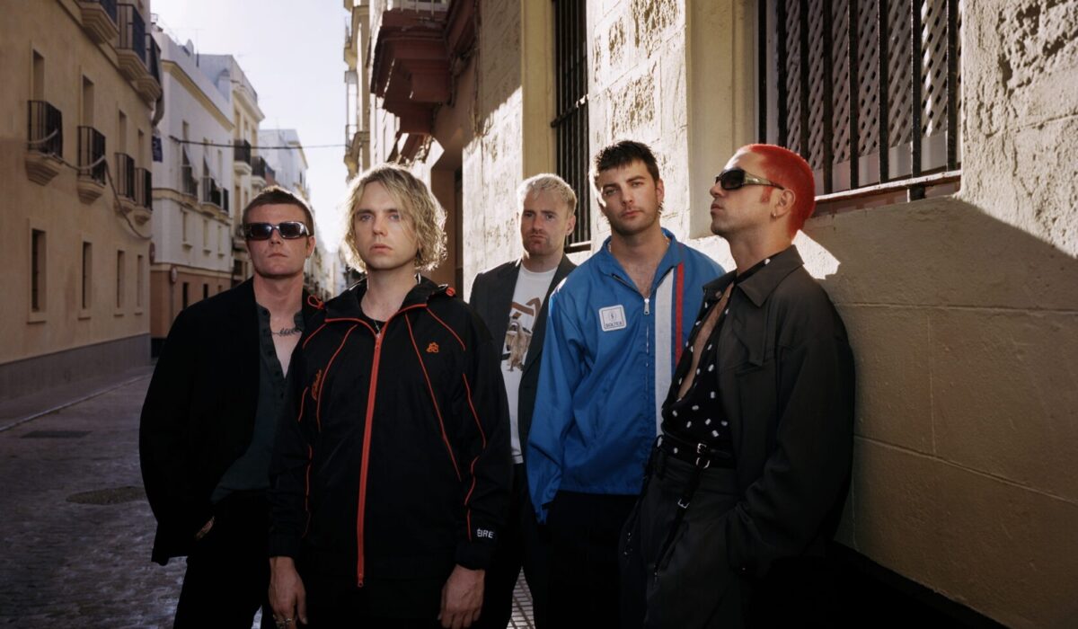 Fontaines D.C. posing in a sunlit Spanish street, the era of the Fontaines D.C. Dopamine Chamber album