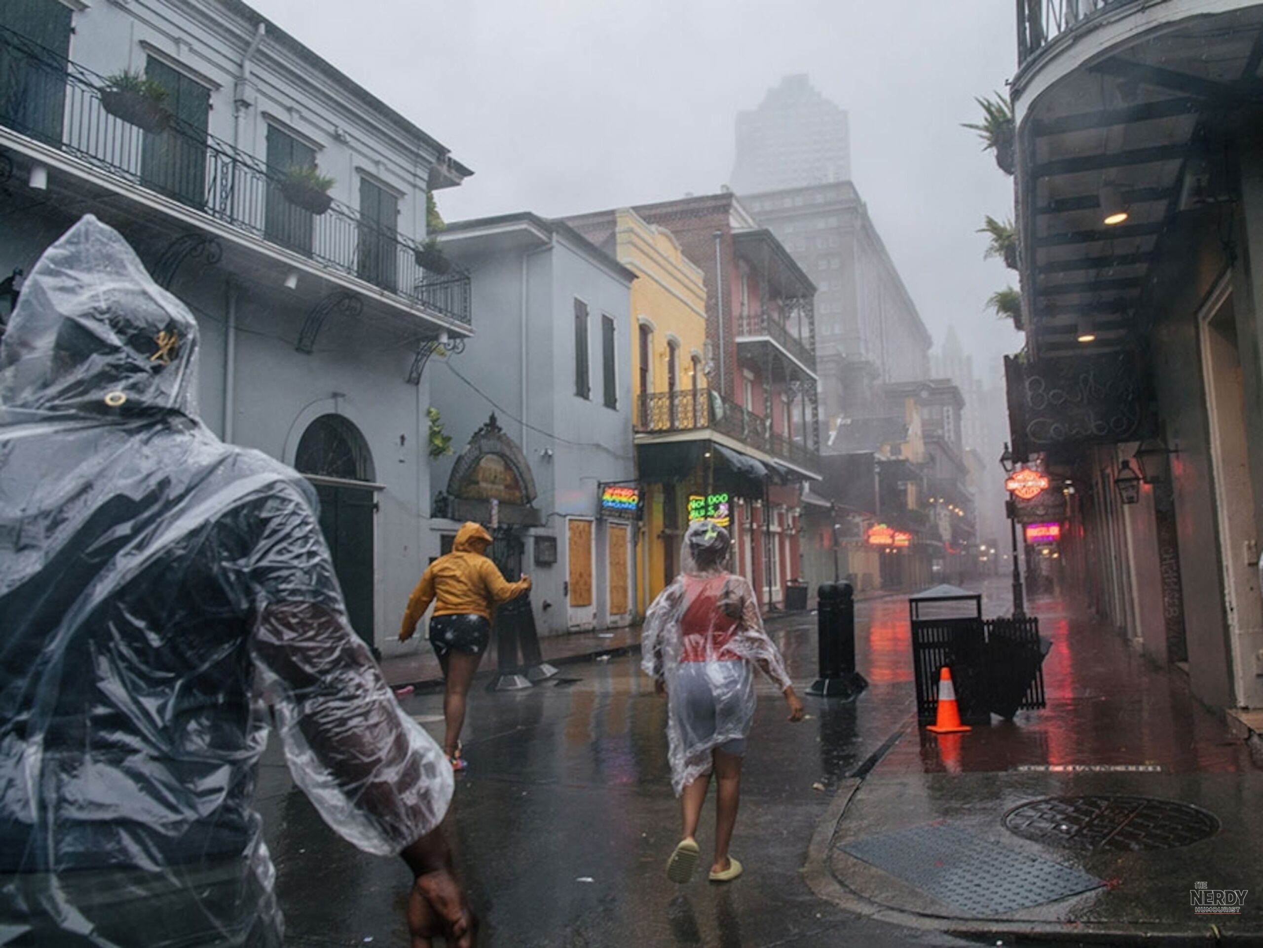 People in rain ponchos walk a rain-soaked New Orleans French Quarter street during the Gulf Coast flash flood threat storms weekend