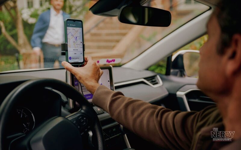 A Lyft driver checking the Lyft app on a mounted phone during a pickup, relevant to the Lyft California settlement for drivers