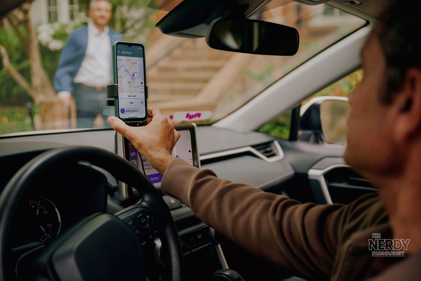 A Lyft driver checking the Lyft app on a mounted phone during a pickup, relevant to the Lyft California settlement for drivers