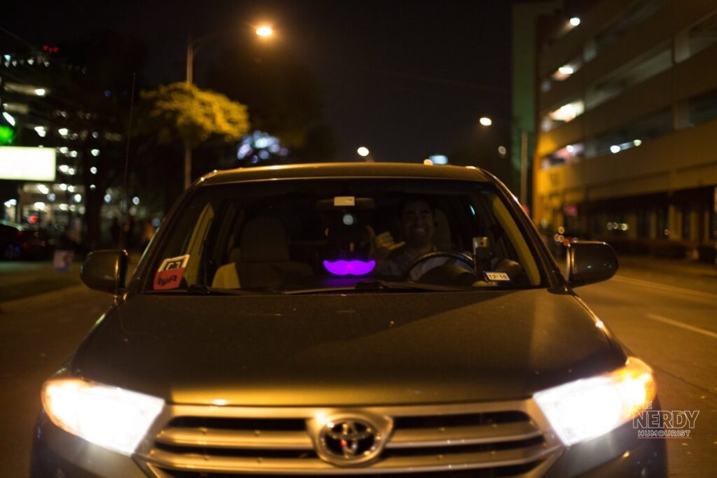 A Lyft rideshare car with the glowing pink Lyft emblem at night, illustrating the Lyft California settlement story