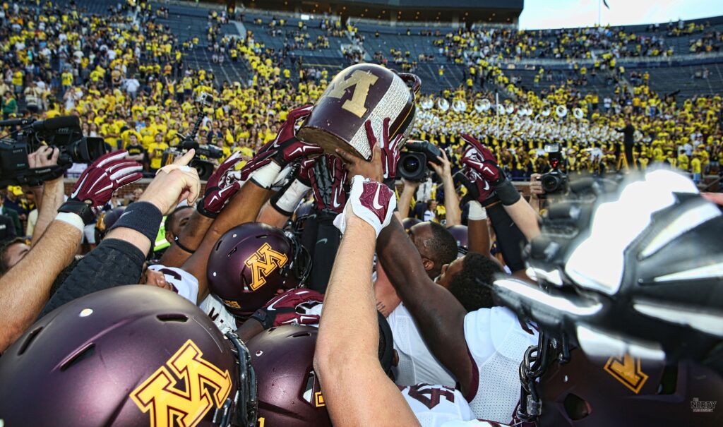 Minnesota Gophers players hoist the Little Brown Jug in a rivalry celebration — Minnesota upsets Michigan 20-14