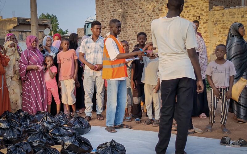 A Sudanese volunteer in an orange vest organizes an aid distribution at an Emergency Response Room in Sudan, ahead of the Nobel Peace Prize 2026 announcement — the ERR volunteer network is the bookmakers' 3/1 favorite.