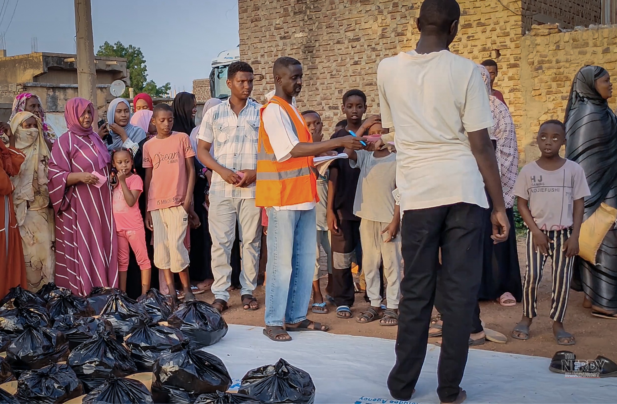 A Sudanese volunteer in an orange vest organizes an aid distribution at an Emergency Response Room in Sudan, ahead of the Nobel Peace Prize 2026 announcement — the ERR volunteer network is the bookmakers' 3/1 favorite.