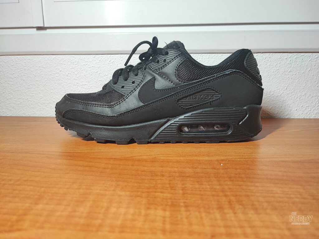 A black Nike Air Max 90 sneaker photographed on a wooden table, illustrating Nike's product lineup amid the weak Nike stock earnings forecast