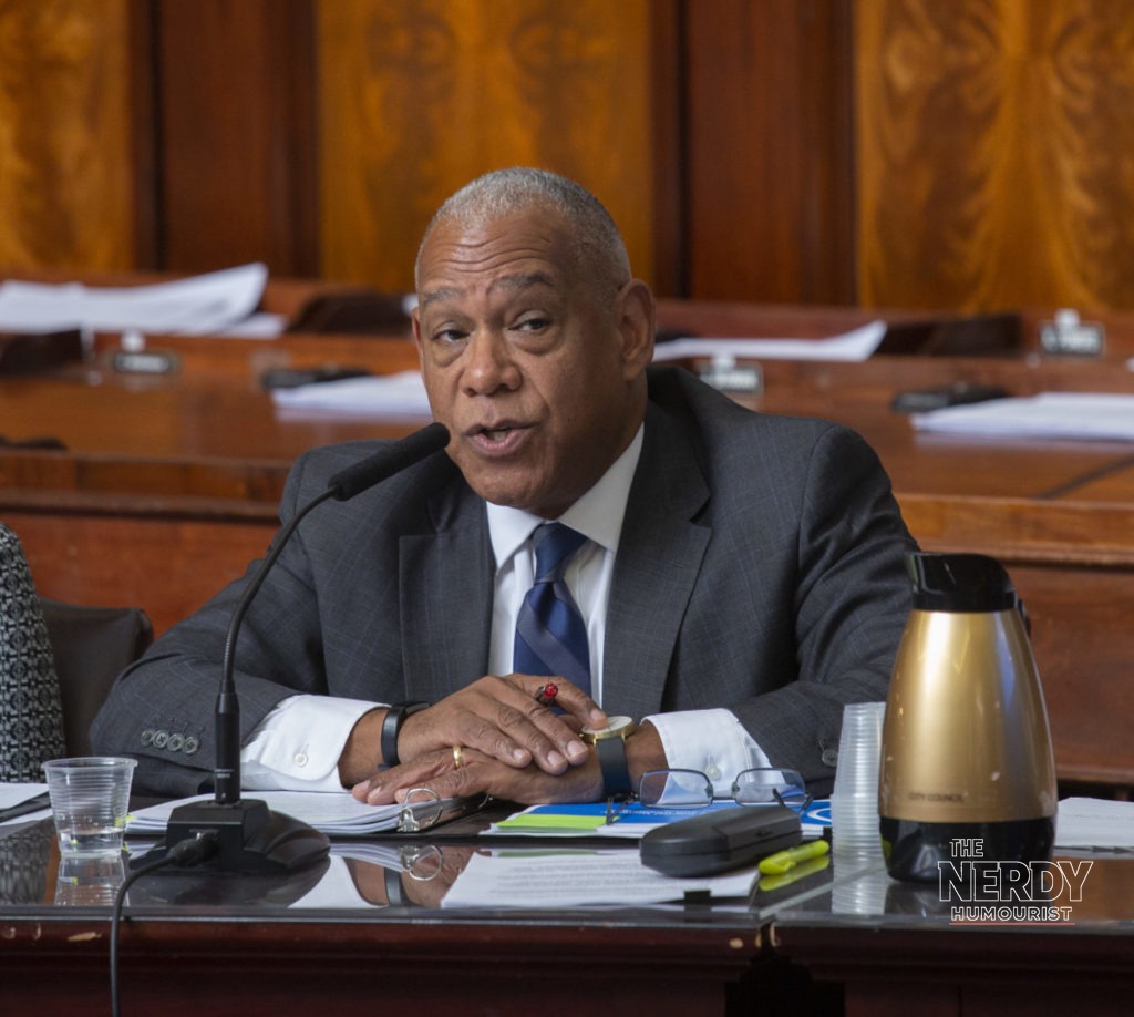 A New York City Council member speaking at a hearing — the setting for the NYC AI hearing October 5, the first sworn testimony by major AI firms