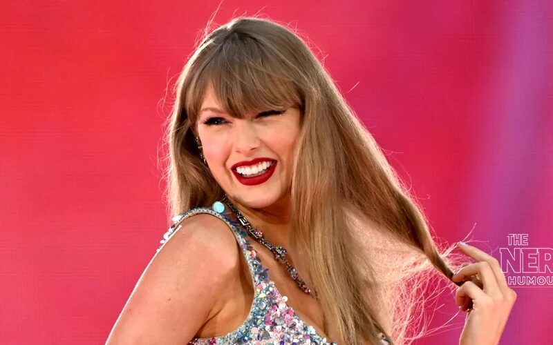 Taylor Swift smiling in a sequined outfit at the 2026 iHeartRadio Music Awards — Patient Zero is her 16th Billboard Hot 100 No. 1